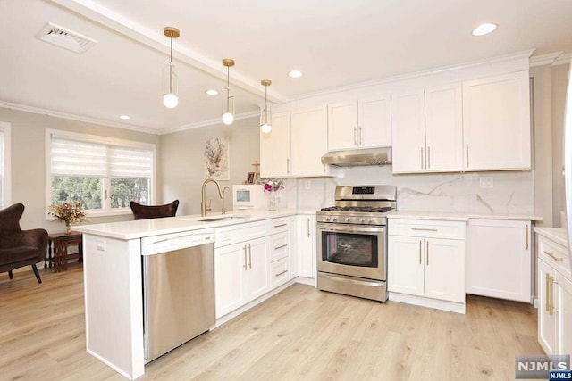 kitchen with pendant lighting, white cabinets, appliances with stainless steel finishes, light hardwood / wood-style floors, and kitchen peninsula