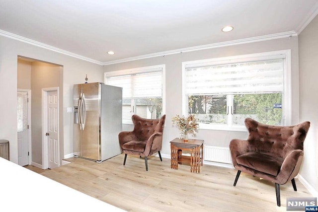 living area featuring plenty of natural light, light wood-type flooring, and ornamental molding