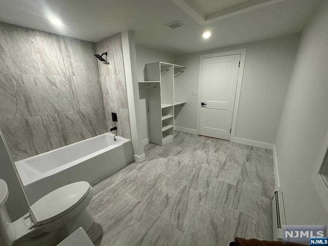 bathroom featuring tiled shower / bath combo and toilet