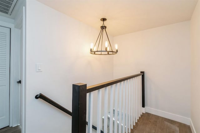 stairs with wood-type flooring and a notable chandelier