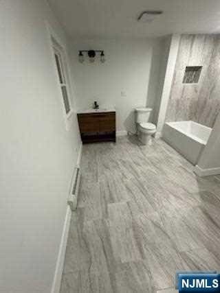 bathroom with hardwood / wood-style floors, toilet, and a baseboard heating unit