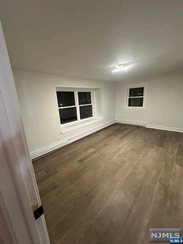 empty room featuring dark hardwood / wood-style floors and a baseboard heating unit