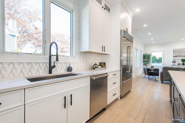 kitchen featuring white cabinetry, sink, decorative backsplash, light stone counters, and stainless steel appliances