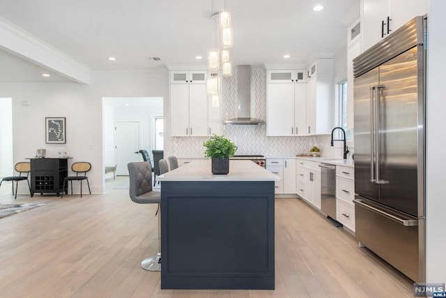 kitchen with white cabinets, stainless steel appliances, and wall chimney range hood