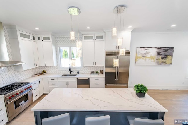 kitchen featuring hanging light fixtures, a breakfast bar area, white cabinets, and premium appliances