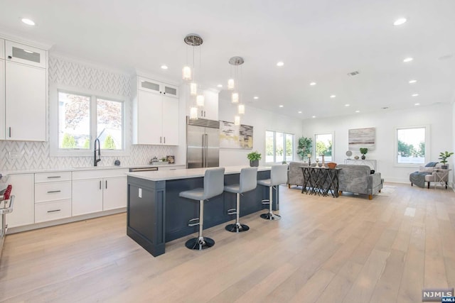 kitchen with white cabinetry, pendant lighting, a kitchen island, and stainless steel built in refrigerator