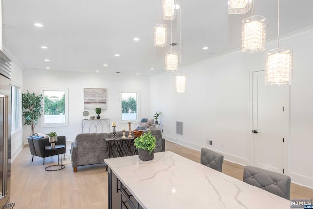 dining space with crown molding, a chandelier, and light wood-type flooring