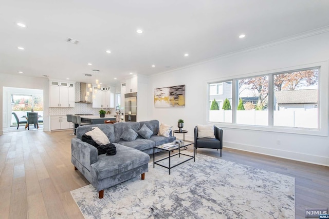 living room with crown molding and light hardwood / wood-style flooring