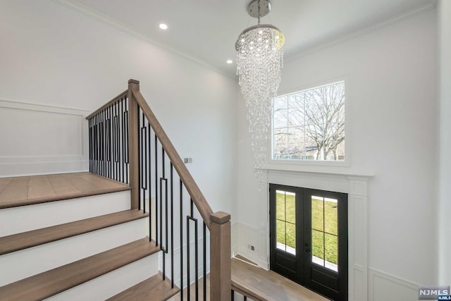 foyer featuring an inviting chandelier, ornamental molding, and french doors