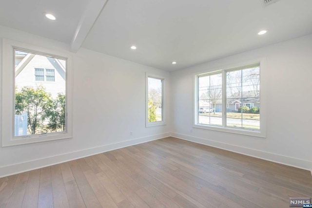 unfurnished room with a healthy amount of sunlight and hardwood / wood-style floors