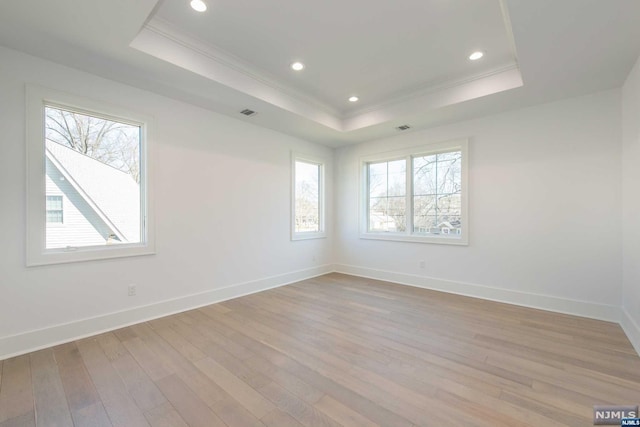 spare room with ornamental molding, a tray ceiling, and light hardwood / wood-style flooring