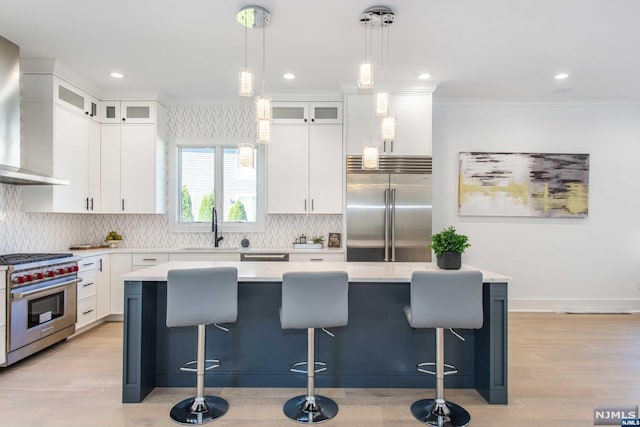 kitchen featuring white cabinetry, premium appliances, wall chimney range hood, and a kitchen island