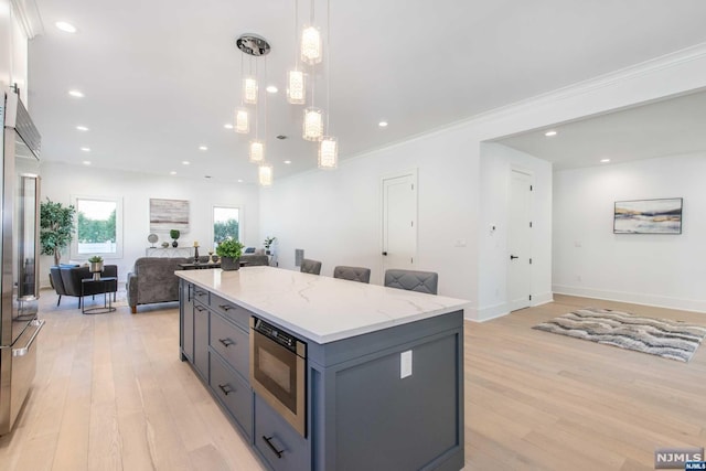 kitchen featuring hanging light fixtures, a kitchen island, light hardwood / wood-style floors, and appliances with stainless steel finishes