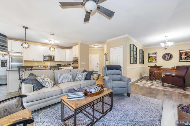 living room with sink, ceiling fan with notable chandelier, dark hardwood / wood-style flooring, and crown molding