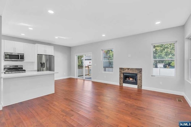 unfurnished living room with hardwood / wood-style floors and a high end fireplace