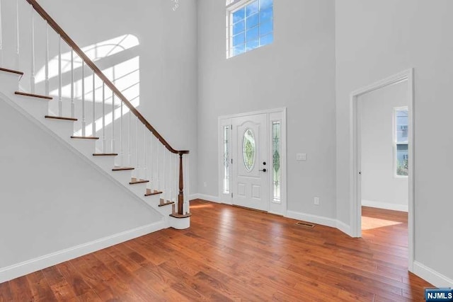 foyer entrance featuring a towering ceiling and wood-type flooring