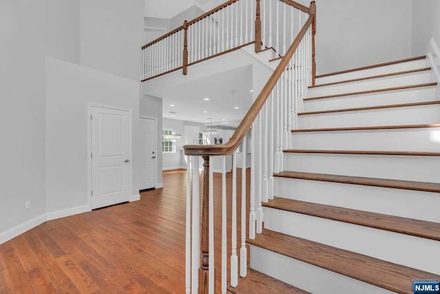 stairs featuring a high ceiling and hardwood / wood-style flooring