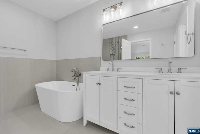 bathroom with a bathing tub, vanity, and tile walls