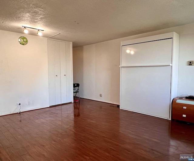 unfurnished bedroom featuring a textured ceiling and dark hardwood / wood-style flooring