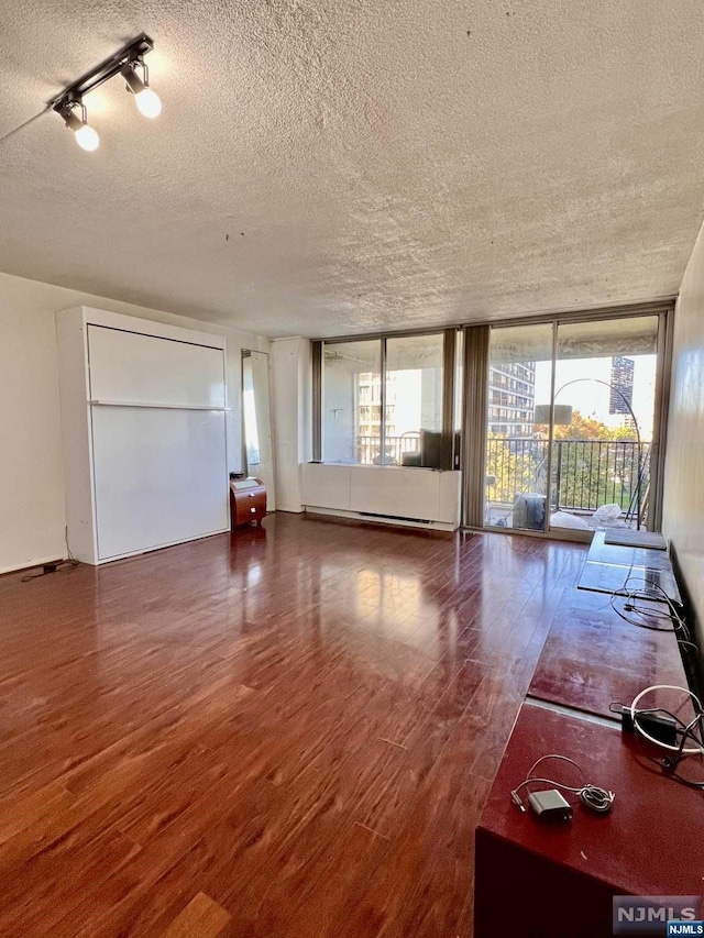 unfurnished living room with a textured ceiling, dark hardwood / wood-style floors, and expansive windows