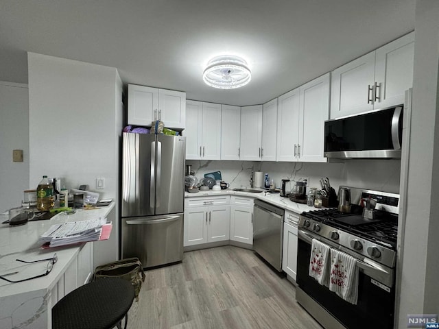 kitchen featuring white cabinets, stainless steel appliances, and light hardwood / wood-style floors