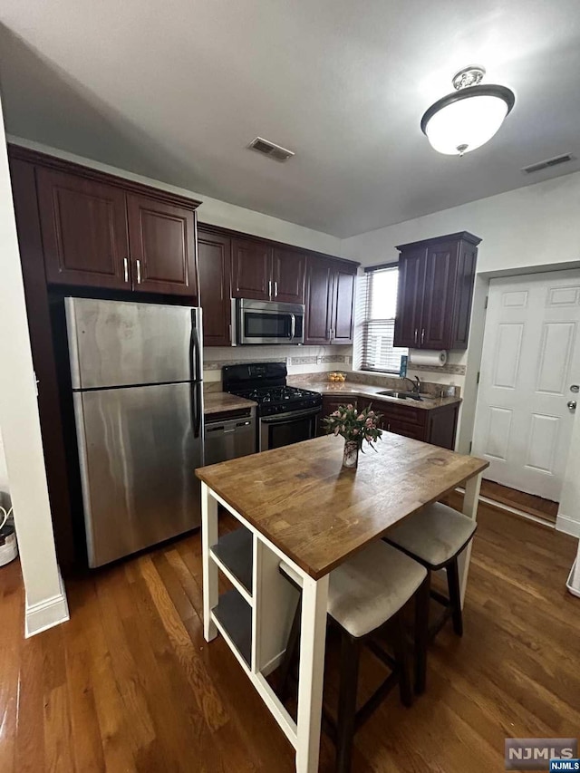 kitchen with a kitchen island, dark hardwood / wood-style flooring, dark brown cabinetry, and stainless steel appliances