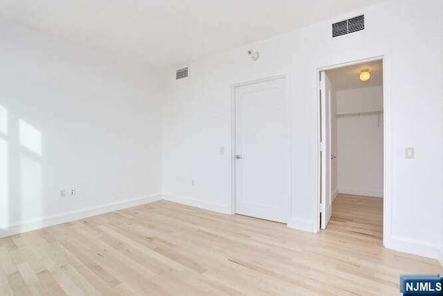 unfurnished bedroom featuring light hardwood / wood-style floors and a spacious closet