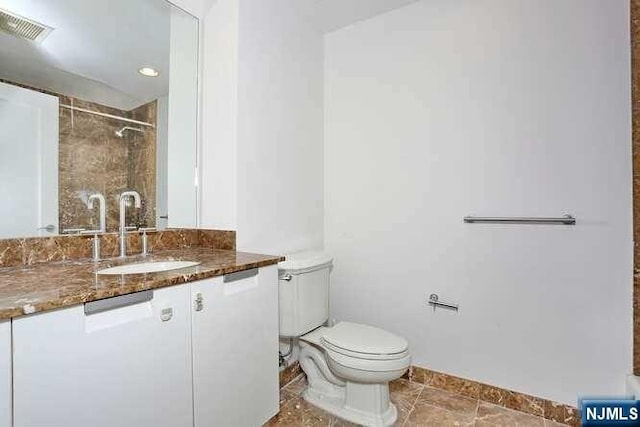 bathroom featuring vanity, toilet, and tiled shower