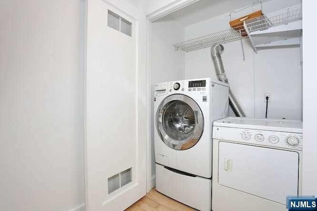 washroom with light hardwood / wood-style floors and independent washer and dryer