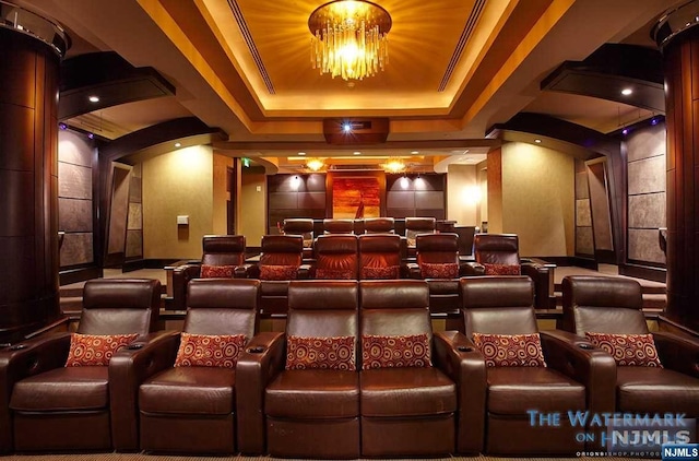 cinema featuring a raised ceiling, crown molding, and a chandelier