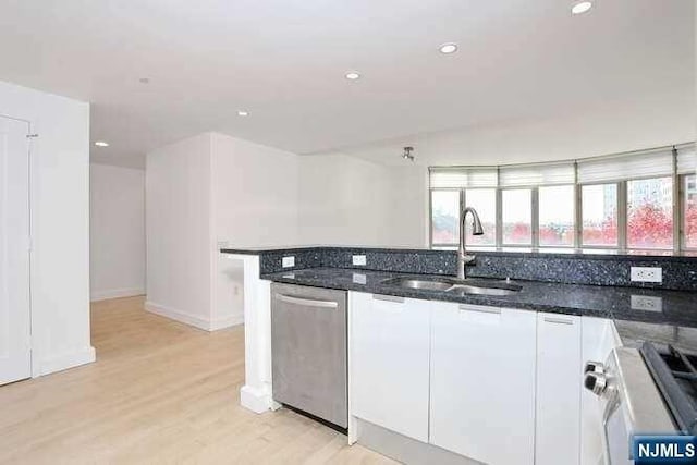 kitchen with appliances with stainless steel finishes, white cabinetry, sink, and dark stone counters