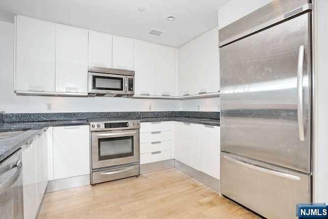 kitchen featuring white cabinets, light hardwood / wood-style floors, and appliances with stainless steel finishes