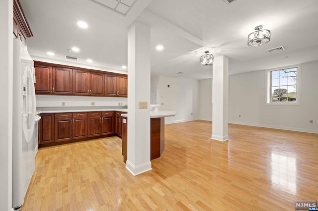 kitchen with light hardwood / wood-style floors, white refrigerator with ice dispenser, kitchen peninsula, and a chandelier