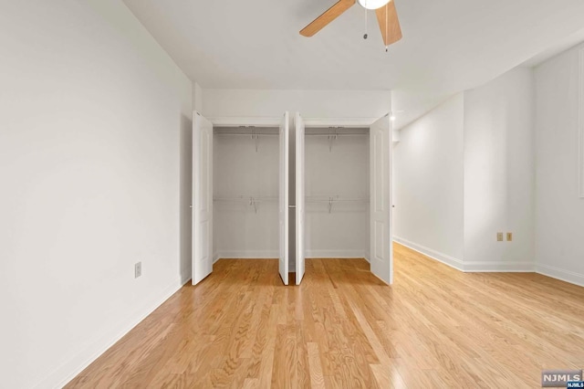 unfurnished bedroom with light hardwood / wood-style floors, ceiling fan, and multiple closets