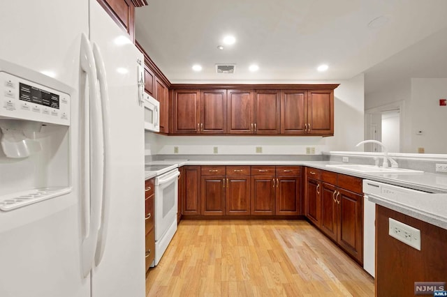 kitchen with sink, white appliances, and light wood-type flooring