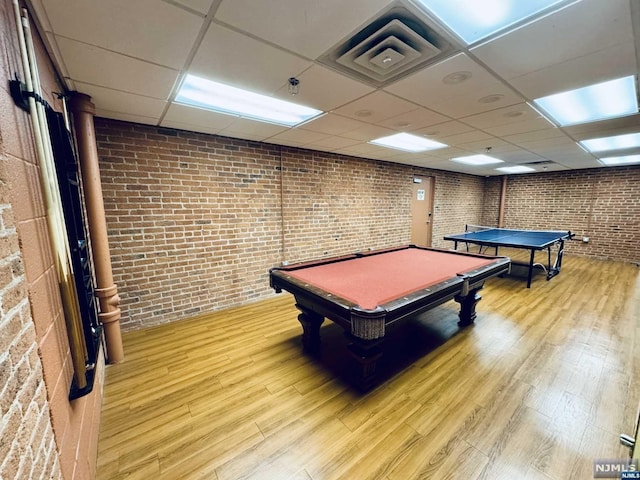 game room with a paneled ceiling, billiards, brick wall, and hardwood / wood-style flooring