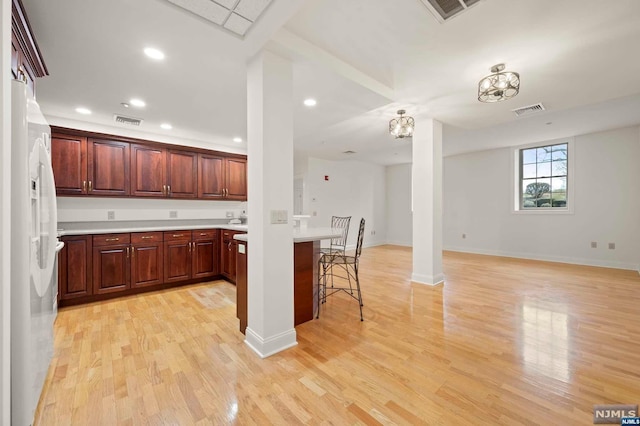 kitchen with a breakfast bar, light hardwood / wood-style flooring, and white fridge