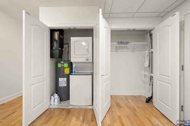 utility room with electric water heater and stacked washer and dryer