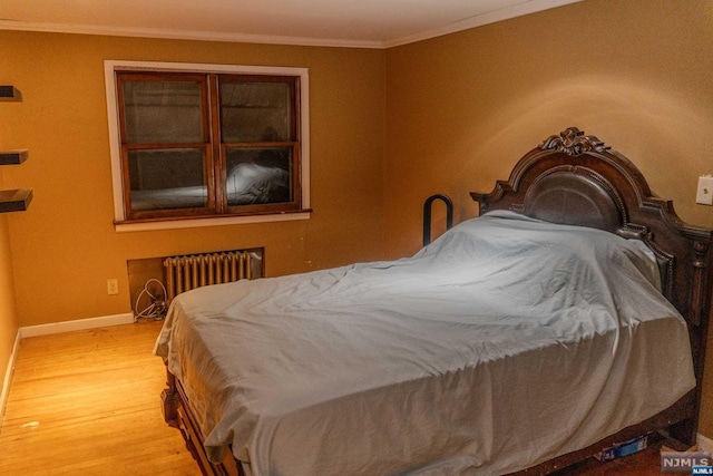 bedroom with light wood-type flooring, radiator heating unit, and ornamental molding