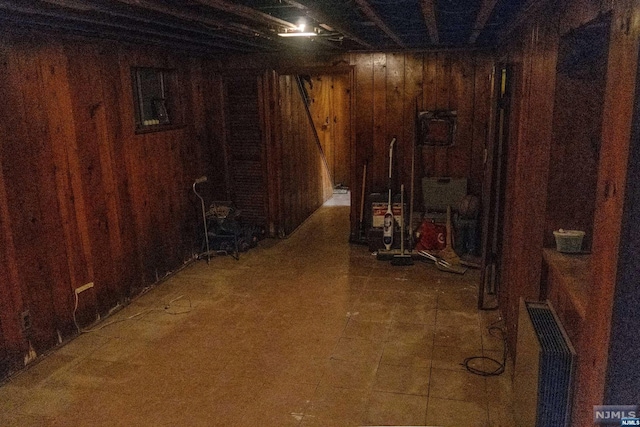 basement with radiator and wooden walls