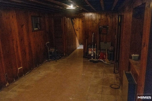 basement featuring wooden walls and radiator heating unit