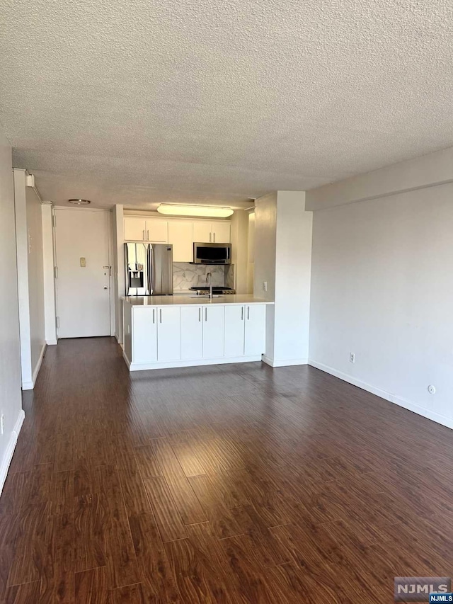 kitchen with dark wood-type flooring, sink, kitchen peninsula, stainless steel appliances, and white cabinets