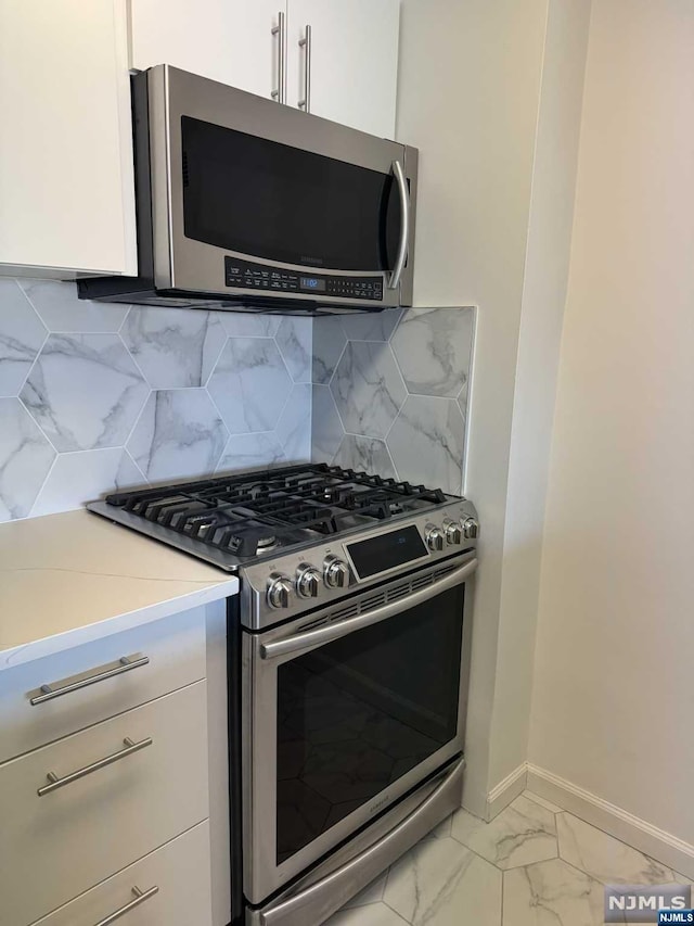 kitchen with tasteful backsplash, appliances with stainless steel finishes, and white cabinets