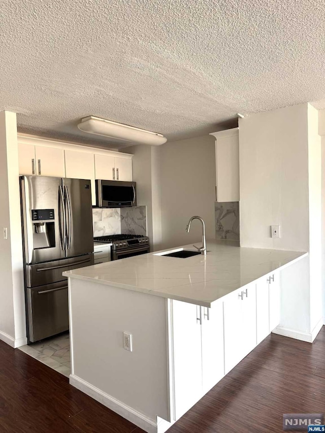 kitchen featuring white cabinetry, appliances with stainless steel finishes, sink, and kitchen peninsula