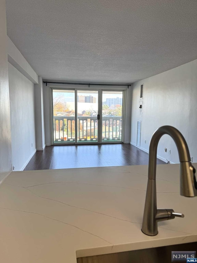 unfurnished room featuring dark hardwood / wood-style floors, sink, and a textured ceiling