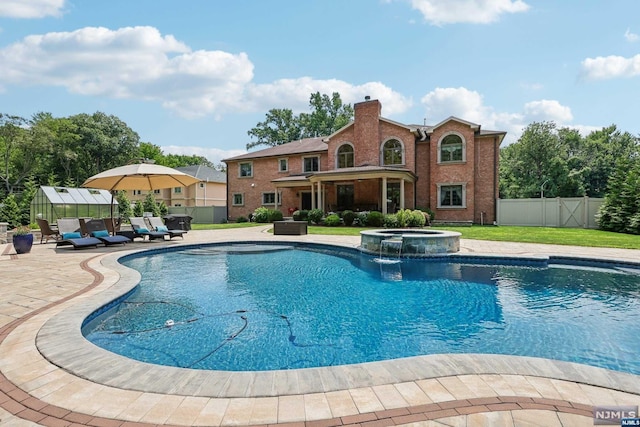 view of swimming pool with an in ground hot tub, an outbuilding, and pool water feature