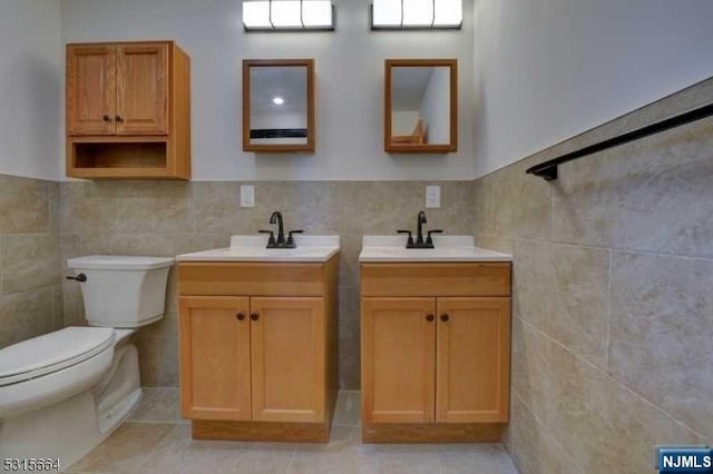 bathroom featuring tile patterned flooring, vanity, toilet, and tile walls