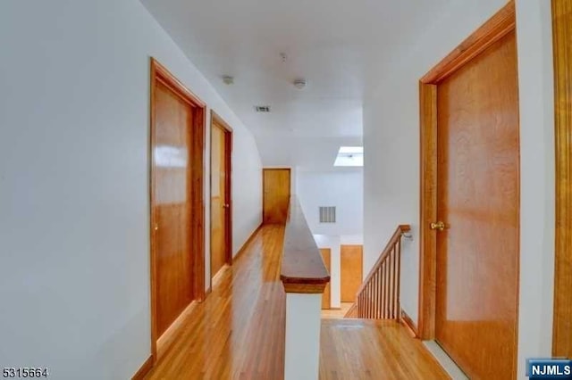 corridor with a skylight and light hardwood / wood-style flooring