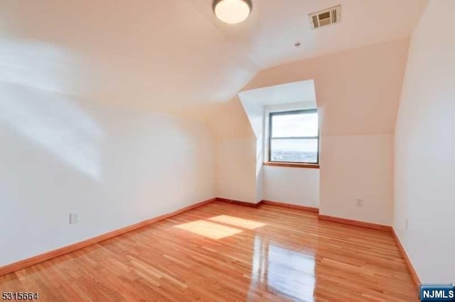 bonus room with light hardwood / wood-style floors and vaulted ceiling