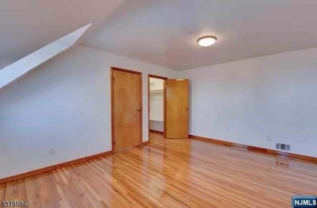 bonus room with a skylight and light wood-type flooring